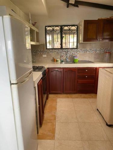 a kitchen with a white refrigerator and wooden cabinets at Finca de Descanso Villa Edelmira in Yumbo