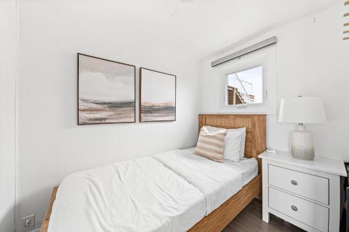 a white bedroom with a bed and two pictures on the wall at The Birch in Wellington