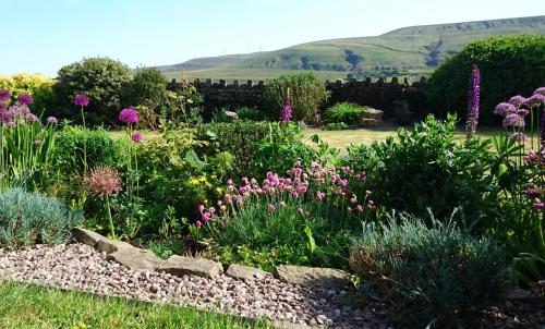 einen Garten mit Blumen und einer Steinmauer in der Unterkunft Parkin House Guest House in Todmorden