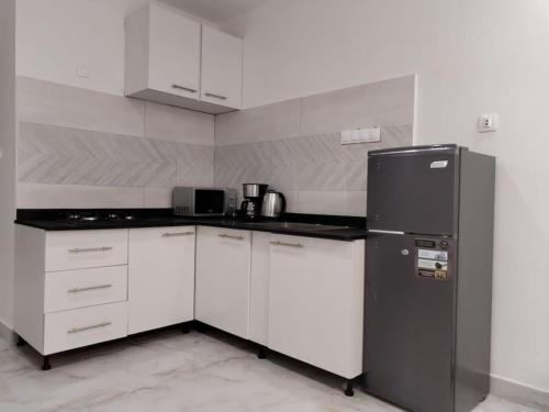 a kitchen with white cabinets and a black refrigerator at La Suite Diam Rekk in Dakar