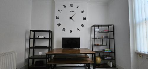 a clock on a wall with a table and shelves at Tower Bridge(TB1) Exclusive Two bedroom apartment in London