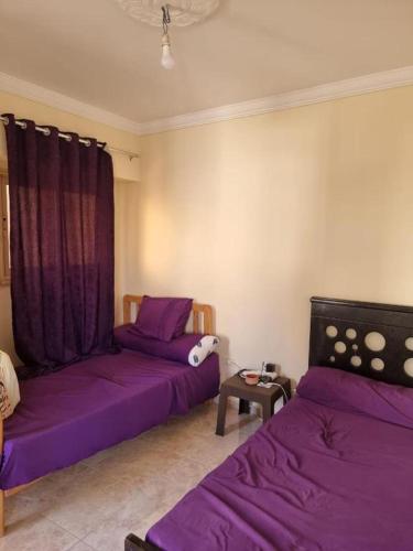 two beds in a room with purple sheets at Taher's family -by bed- "no Egyptians" in Cairo