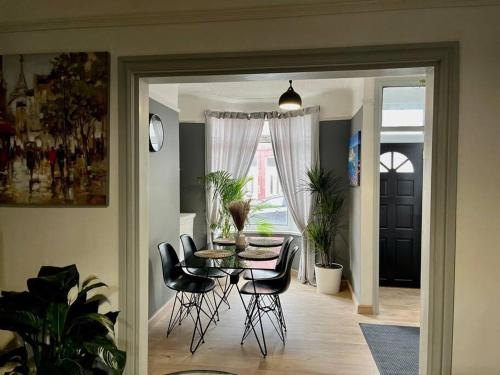 a dining room with a table and black chairs at Cityscape-Cosy House By Anfield in Liverpool