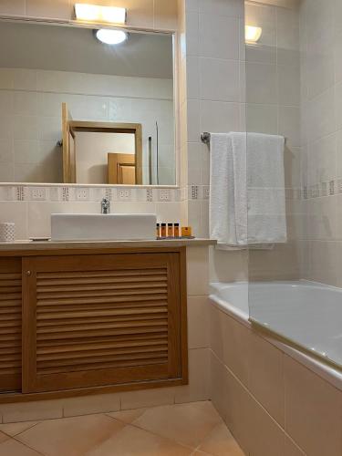 a bathroom with a sink and a tub and a mirror at Margarida Apartment in Luz