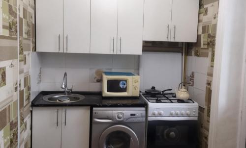 a small kitchen with a washing machine and a microwave at Квартира in Taraz