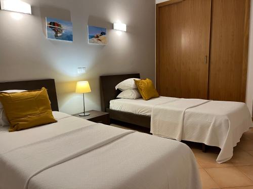 a hotel room with two beds with yellow pillows at Margarida Apartment in Luz