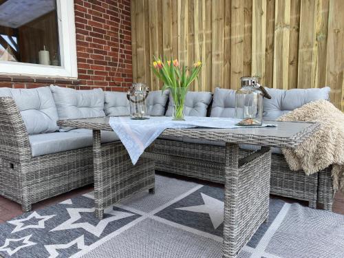 a wicker couch and table on a patio at Ferienhaus Norddeichkieker in Norddeich