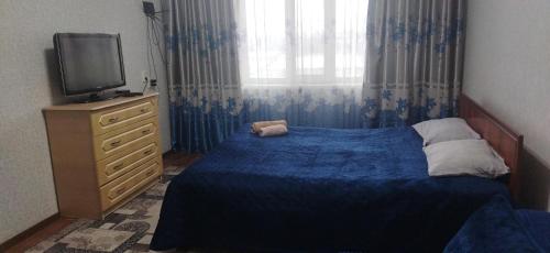 - une chambre avec un lit bleu et une télévision dans l'établissement Квартира, à Taraz