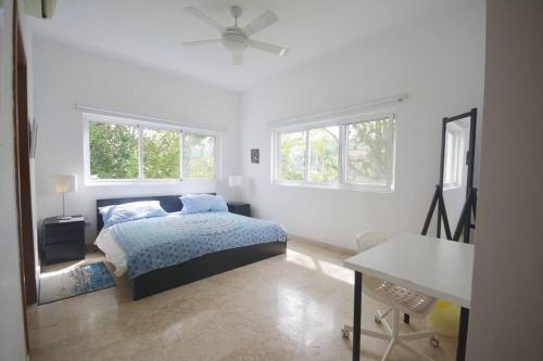 a white bedroom with a bed and two windows at Magnifique appartement vue mer in Las Terrenas