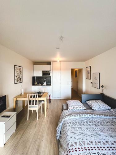 a bedroom with two beds and a desk and a kitchen at Studio Le Hésingue- Near Airport, Swiss & German board in Saint-Louis