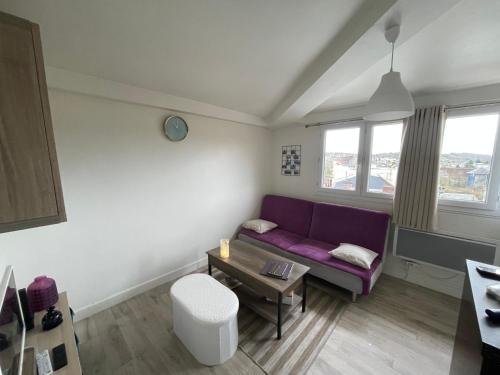een woonkamer met een paarse bank en een tafel bij Cocoon’Lis, 2 pièces en plein centre ville in Lisieux