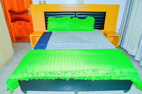 - une chambre avec un lit et des oreillers verts dans l'établissement AIRPORT COMFORT APARTMENT MILITARY HOSPITAL, à Kigali