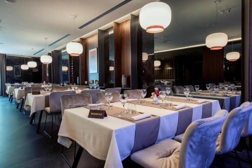 a restaurant with long tables and chairs and lights at Seraphine Plaza in Peje