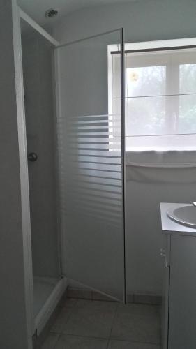 une salle de bain blanche avec une douche et un lavabo dans l'établissement Charmante petite maison bretonne, à Rosporden
