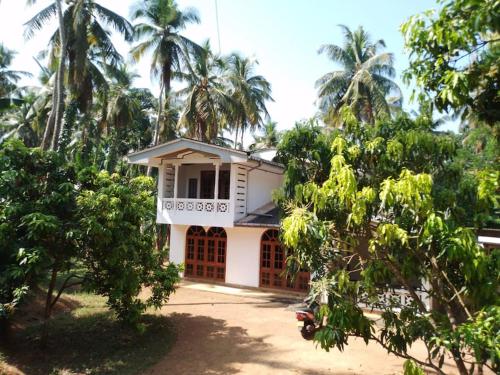 Holiday Home in Mirigama في Mirigama: بيت ابيض امامه اشجار النخيل