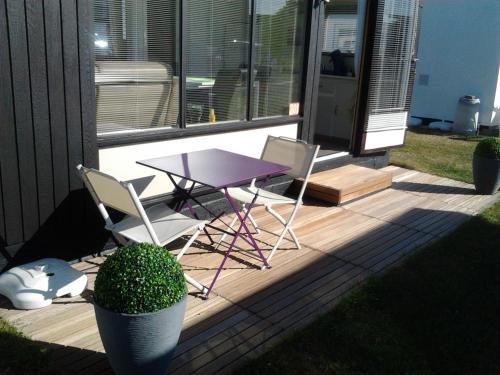 een paarse tafel en twee stoelen op een houten terras bij Noordzee 1 in De Haan