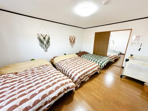 two beds in a room with wooden floors at Kaito/9min walk to Noboribetsu st. in Tomiura