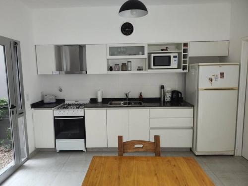 a kitchen with white cabinets and a sink and a refrigerator at Duplex Victoria in Luján
