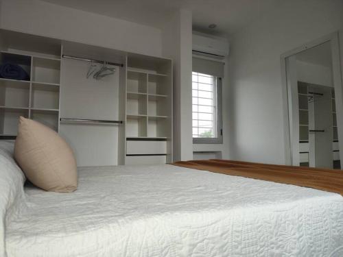 a white bedroom with a large bed and a window at Duplex Victoria in Luján