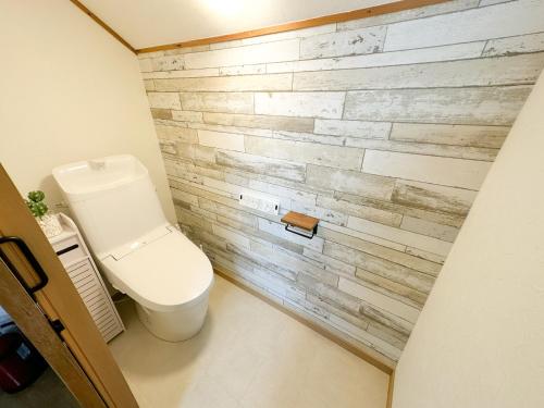 a bathroom with a toilet and a brick wall at KAITO 9min walk to Noboribetsu st in Noboribetsu