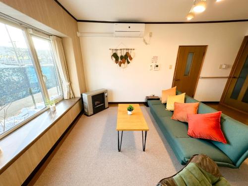 a living room with a green couch and a table at KAITO 9min walk to Noboribetsu st in Noboribetsu