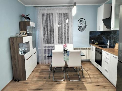 a kitchen with a glass table and white chairs at Apartament u Bączków in Gdynia