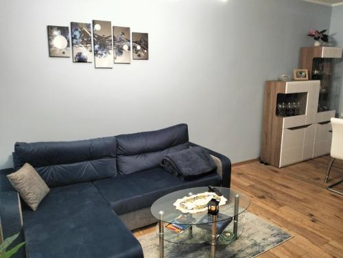 ein Wohnzimmer mit einem blauen Sofa und einem Glastisch in der Unterkunft Apartament u Bączków in Gdynia