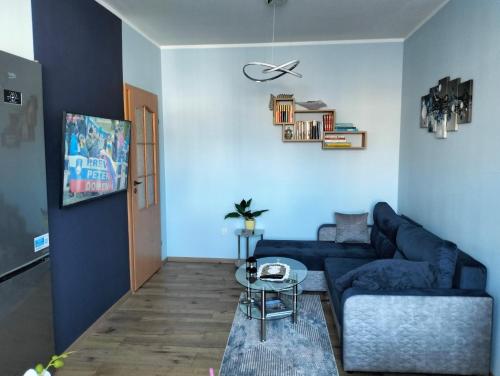 ein Wohnzimmer mit einem blauen Sofa und einem Tisch in der Unterkunft Apartament u Bączków in Gdynia