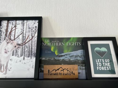 a shelf with two pictures and a picture of a deer at Sixty Six Degrees North - Lapland Home & Forest in Överkalix