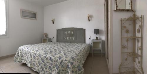 a bedroom with a bed with a comforter on it at Maison Vent du Sud in Saint-Trojan-les-Bains