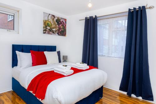 SydenhamにあるSpacious 3BR, 5min Penge St, Crystal Palace Parkのベッドルーム1室(大型ベッド1台、赤と白の枕付)