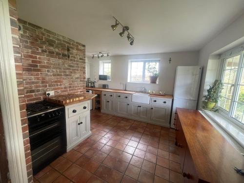 a kitchen with white cabinets and a brick wall at Charming cottage near airport in Yatton