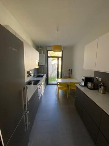 une cuisine avec des armoires blanches et une table à l'intérieur dans l'établissement Les domaniales du Pape - Maison 92m2, à Pessac