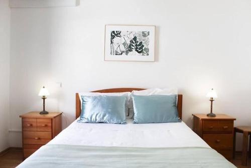 a bedroom with a bed with blue pillows and two night stands at Seashell Bay - Beach House - in São Martinho do Porto