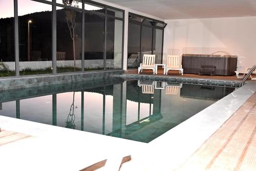 a house with a swimming pool with two chairs and a tub at L'escale Hôtel & Spa By 7AV HOTELS in Ouazzane