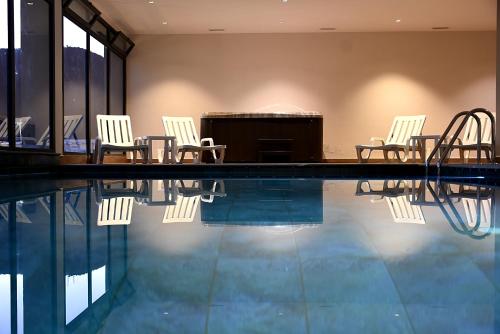 a pool with chairs and a piano in a building at L'escale Hôtel & Spa By 7AV HOTELS in Ouazzane
