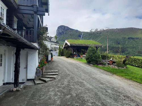 an empty road in a village with mountains in the background at Fjordgaestehaus in Innfjorden