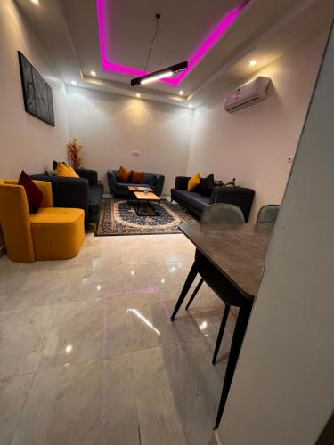 a living room with couches and a table and purple lights at شقق الروشن الجوفي in Al Fayşalīyah