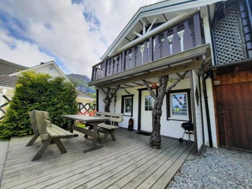 a wooden deck with a picnic table and a house at Fjordgaestehaus in Innfjorden