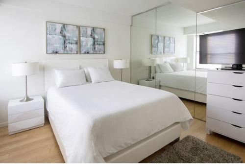 een witte slaapkamer met een groot bed en een televisie bij PlanURstay - Spacious Midtown West Fully-Serviced - 1BR & 1BTH in New York