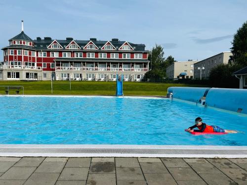 a person swimming in a large pool with a building in the background at Sixty Six Degrees North - Lapland Home & Forest in Överkalix