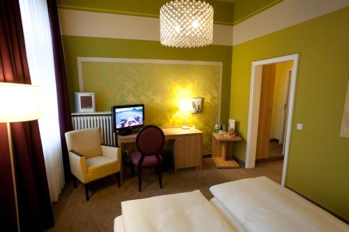 Schlafzimmer mit einem Bett, einem Schreibtisch und einem Stuhl in der Unterkunft Hotel Schepers in Gronau