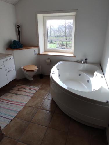 baño con bañera, aseo y ventana en Emily's Garden en Lintrup