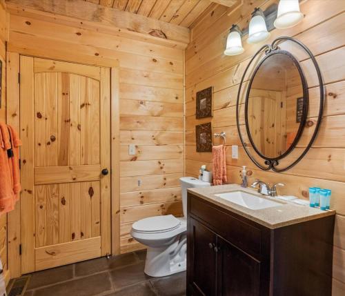 La salle de bains est pourvue de toilettes, d'un lavabo et d'un miroir. dans l'établissement 3br Alpine Retreat With Hot Tub And Theater Room, à Pigeon Forge