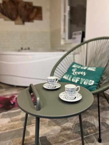 a table with two cups of coffee and a telephone at Opsesija SPA in Kragujevac