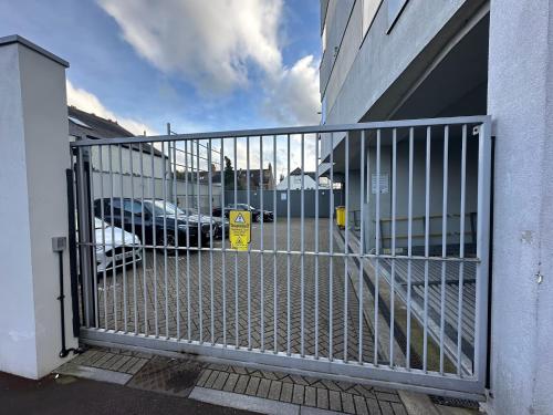 a gate to a parking lot with a car behind it at Modern Flat in Leigh Broadway in Leigh-on-Sea