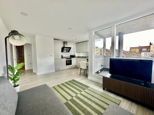 a living room with a large tv and a large window at Modern Flat in Leigh Broadway in Leigh-on-Sea