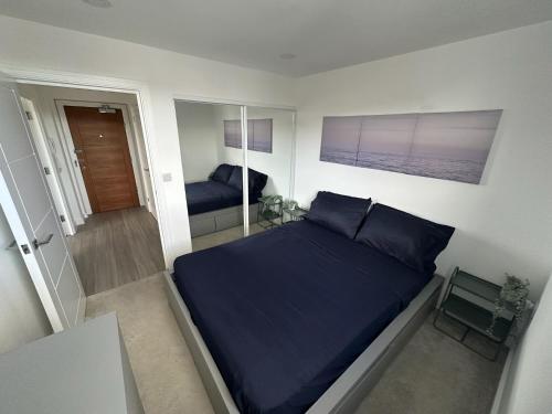 1 dormitorio con cama azul y espejo en Modern Flat in Leigh Broadway, en Leigh-on-Sea