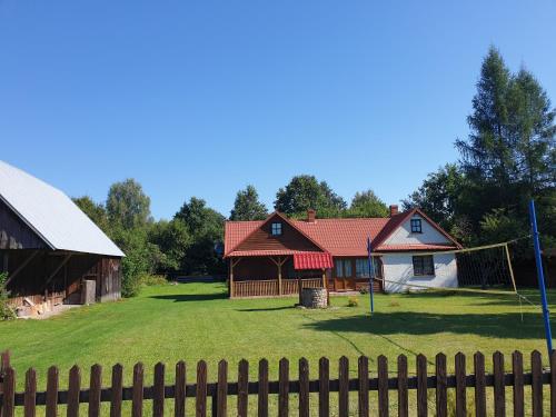 una casa con una valla delante de un patio en Leśny domek, en Białowieża