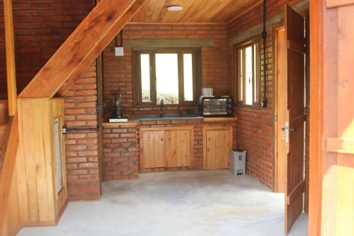 a kitchen with a sink and a brick wall at Vila Sol Cabanas in Lontras